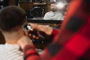coiffeur magasin. homme avec épouse dans barbier chaise, coiffeur salon de coiffure coiffant le sien cheveux. photo