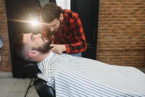 coiffeur magasin. homme avec épouse dans barbier chaise, coiffeur salon de coiffure coiffant le sien cheveux. photo