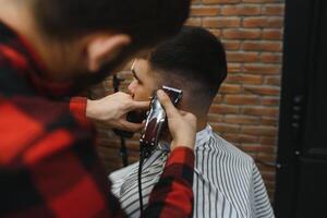 sérieux Jeune barbu homme avoir la Coupe de cheveux par coiffeur. salon de coiffure thème. photo