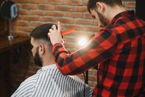 sérieux Jeune barbu homme avoir la Coupe de cheveux par coiffeur. salon de coiffure thème. photo