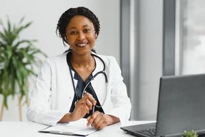 médecine, en ligne un service et soins de santé concept - content souriant africain américain femelle médecin ou infirmière avec casque et portable ayant conférence ou appel à hôpital. photo