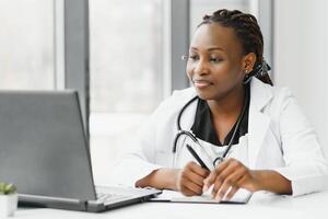 médecine, en ligne un service et soins de santé concept - content souriant africain américain femelle médecin ou infirmière avec casque et portable ayant conférence ou appel à hôpital. photo