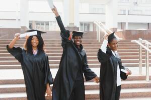 éducation, l'obtention du diplôme et gens concept - groupe de content international élèves dans mortier planches et bachelier robes avec diplômes photo