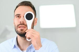 tester de vue. homme est vérification le sien vision à l'intérieur dans le clinique photo