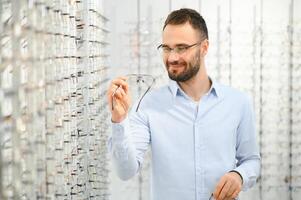 Jeune homme choisir lunettes à optique magasin photo