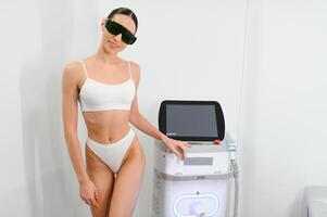 Jeune magnifique femme avec laser cheveux suppression machine dans cosmétologie cabinet photo