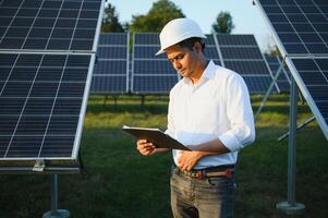 un Indien Masculin ingénieur travail sur une champ de solaire panneaux. le concept de renouvelable énergie photo