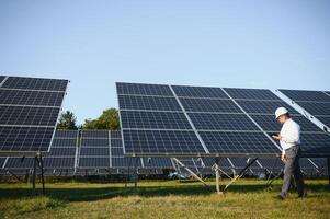 solaire Puissance plante. homme permanent près solaire panneaux. renouvelable énergie photo