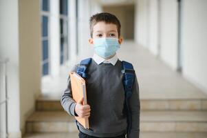 peu écolier portant une masque pendant un déclenchement de couronne et grippe virus, protection contre maladies pour enfants, masque pour le la prévention de corona virus. photo