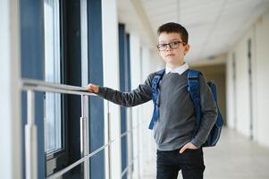 écolier avec cartable et livres dans le école. éducation concept. retour à école. écolier Aller à classe. élégant garçon avec sac à dos. garçon prêt à étude photo