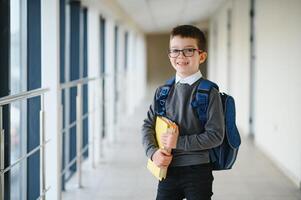 écolier avec cartable et livres dans le école. éducation concept. retour à école. écolier Aller à classe. élégant garçon avec sac à dos. garçon prêt à étude. photo