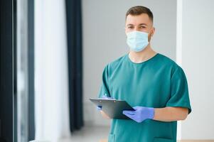 portrait de Masculin médecin portant chirurgical masque est prêt à Aidez-moi les patients avec coronavirus ou convoitise virus. photo