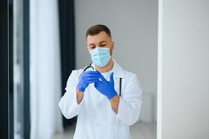 portrait de Masculin médecin portant chirurgical masque est prêt à Aidez-moi les patients avec coronavirus ou convoitise virus. photo