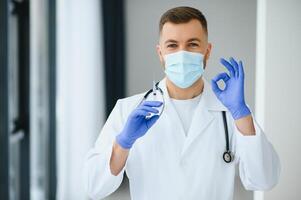 portrait de Masculin médecin portant chirurgical masque est prêt à Aidez-moi les patients avec coronavirus ou convoitise virus photo