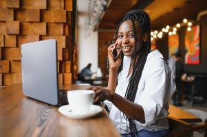 chanceux journée. émotif noir femme à la recherche à ordinateur portable, serrant les poings et en hurlant, travail à café, copie espace photo
