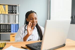 africain femelle médecin parler avec patient faire télémédecine en ligne webcam appel. femme thérapeute conférence sur ordinateur dans éloigné télémédecine portable virtuel discuter. télésanté concept. photo