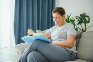 femme dans Accueil séance sur canapé en train de lire livre. photo