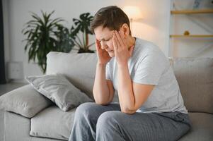 dérangé milieu vieilli plus âgée femme masser les temples émouvant douloureux tête sentiment fort mal de crâne ou migraine concept, triste fatigué stressé personnes âgées Sénior mature femme Souffrance de douleur ou vertiges. photo