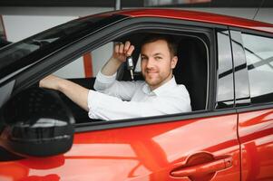 Oui, c'est mon Nouveau auto. client dans voiture concession. Jeune homme avec clés dans main. photo