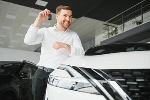 Oui, c'est mon Nouveau auto. client dans voiture concession. Jeune homme avec clés dans main. photo