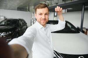 Oui, c'est mon Nouveau auto. client dans voiture concession. Jeune homme avec clés dans main. photo