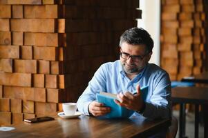 mature Beau homme en train de lire une livre dans une café photo