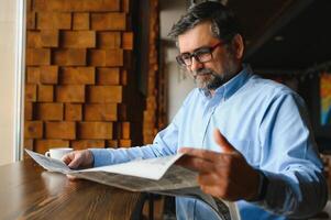 café Pause. homme en buvant café et en train de lire journal dans café bar photo