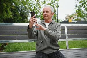 vieux aux cheveux gris homme du repos sur le banc dans été parc photo