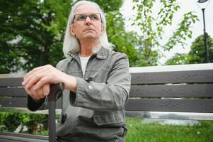 vieux aux cheveux gris homme du repos sur le banc dans été parc photo