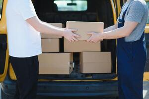 courrier un service pour le livraison de marchandises. Express un service une homme dans une uniforme livre des boites. le employé porte le commande Accueil à le client. photo