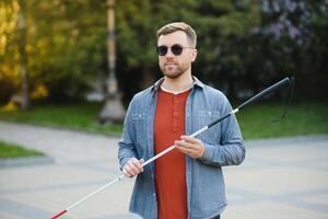 Jeune Beau aveugle homme en marchant avec bâton dans ville photo