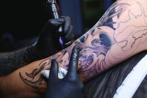 tatouage artiste mains portant gants et en portant une tatouage machine photo