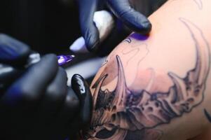 tatouage artiste mains portant gants et en portant une tatouage machine photo