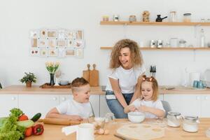 famille apprentissage Nouveau recette ensemble. content maman et des gamins mélange Ingrédients pour fait maison gâteau, tarte ou biscuit pâte dans le cuisine. photo