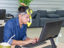 Jeune homme portant une plongée masque Jaune et séance sur une chaise travail dans le bureau. il rêves de le mer car le vacances à venir bientôt. vacances concept photo