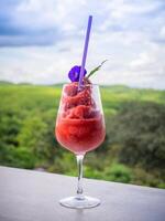 une verre de Frais en bonne santé pastèque smoothie contre le Contexte de ciel, des nuages, et montagnes. en bonne santé nutrition et vitamines photo