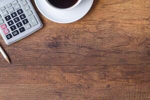 Haut vue de une crayon, calculatrice et une café tasse mis sur en bois table dans le bureau. espace pour texte. bois texture Contexte. affaires et la finance concept photo