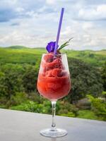 Frais en bonne santé pastèque smoothie dans le verre contre le Contexte de ciel, des nuages, et montagnes. en bonne santé nutrition et vitamines photo