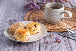 fermer de traditionnel Britanique scones dessert et une biscuit sur une assiette avec une tasse à thé et fleur flou Contexte. espace pour texte. concept de dessert et thé photo