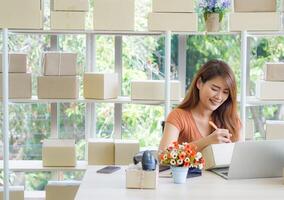 femme d'affaires porte décontractée tissu séance sur une chaise dans le bureau. le travail bureau pour le entrepreneur dans le Bureau a une ordinateur portable, code à barre lecteur préparer pour ordres de les clients photo