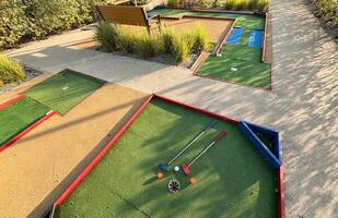 mini golf clubs et des balles de différent couleurs posé sur artificiel herbe. photo