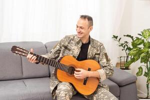 vétéran guitare jouer concept. famille réunion. camouflage uniforme. repos sentiments montrant. patriotique revenir. paralysé soldat photo