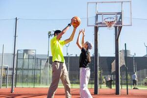 père et adolescent fille en jouant basketball à l'extérieur à tribunal photo