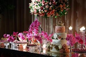 sophistiqué rose à thème fête avec fleurs, bonbons, bougies et fleurs et couronné gâteau photo