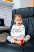 bébé garçon séance sur une patron chaise. petit enfant sur une cuir Bureau chaise. photo