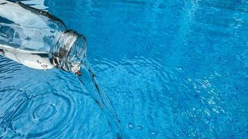 verser l'eau de verre bouteille dans chatoyant bleu avec circulaire ondulations et reflets sur le surface. nettoyer l'eau concept. photo