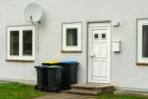 Plastique poubelle canettes près le entrée à une Résidentiel bâtiment. Satellite plat sur le mur photo