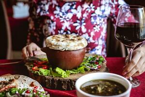 femme séance à table avec assiette de nourriture et verre de du vin photo