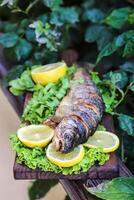 Frais poisson sur Coupe planche avec citrons et salade photo