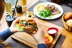 la personne en portant une sandwich dans de face de une assiette de nourriture photo